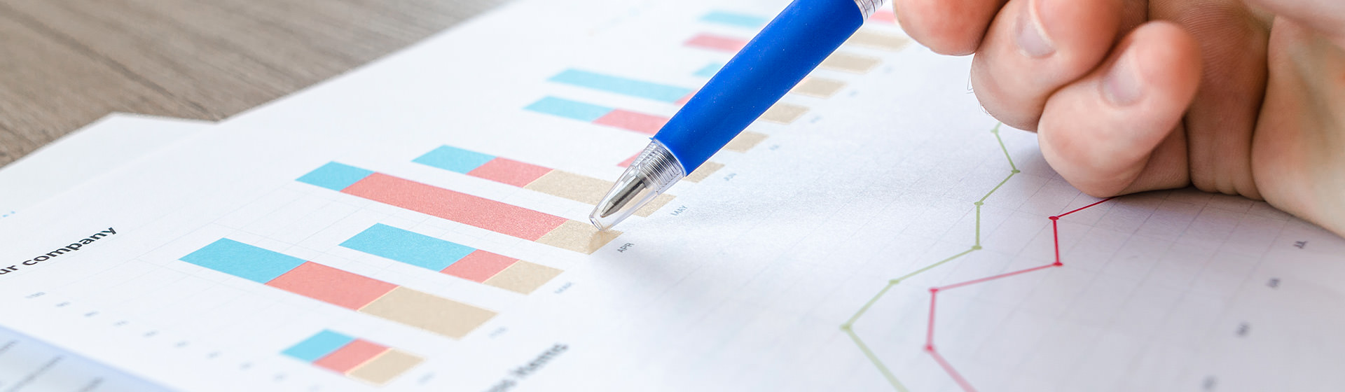 Hand holding pen looking over statistics